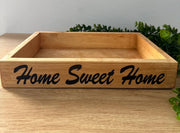 Wooden box with 'Home Sweet Home' engraving on a wooden surface with a gray background