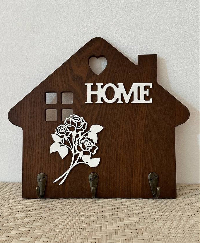 Wooden house-shaped decorative item with 'HOME' and a rose design on a neutral background